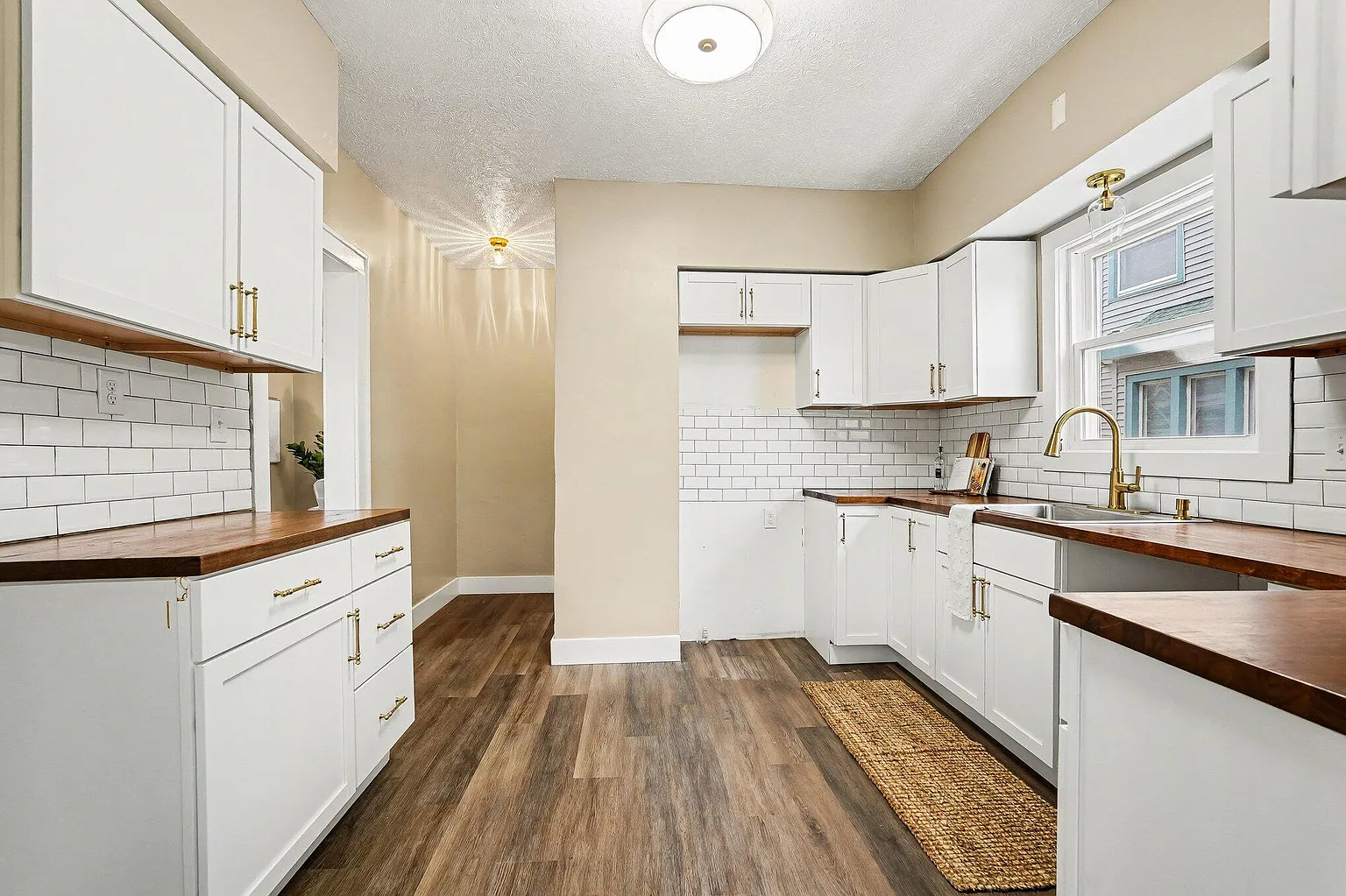 Completed kitchen remodel with white cabinets, wood counters, and subway tile